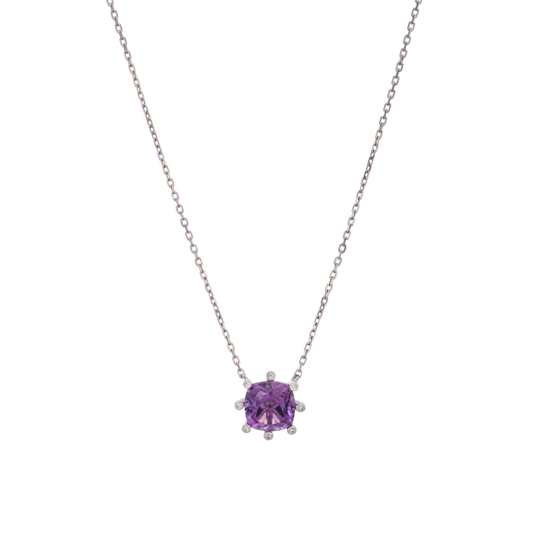 A silver-toned necklace featuring a cushion-cut purple gemstone pendant in a prong setting, flanked by small clear accent stones, shown against a plain white background. 